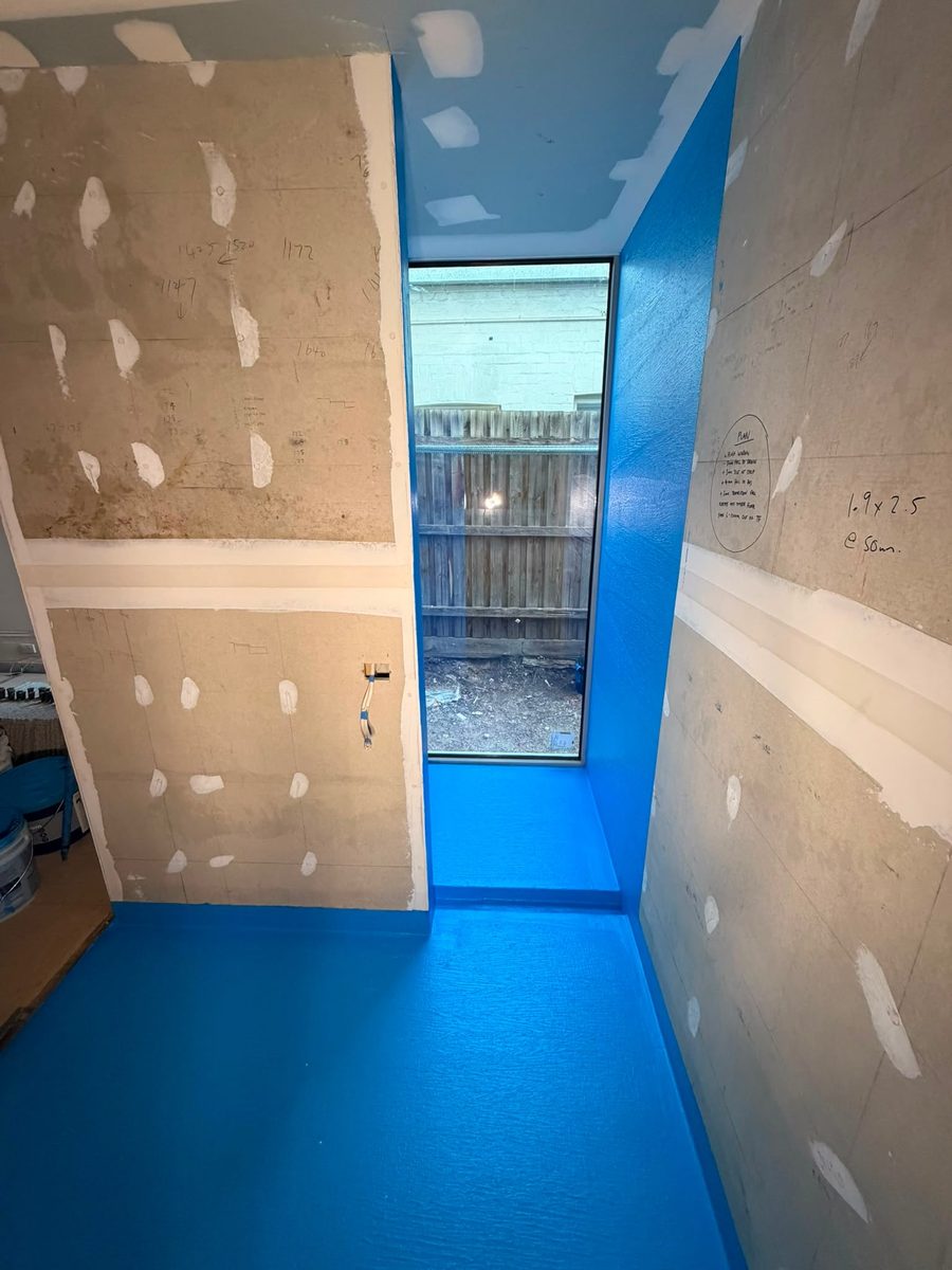 Laundry floor and hob coated in blue waterproofing membrane — photo by Brady Tiling